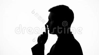 男人表现出沉默的姿态，不透露秘密数据，手指在嘴唇上
